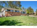 Single-story home with stone accents, green lawn, and mature trees in a quiet neighborhood at 2 Lincoln Pl, Longmont, CO 80501