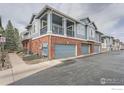 Exterior view of townhome with blue siding, brick accents, garage, and outdoor balcony at 122 Whitehaven Cir, Highlands Ranch, CO 80129