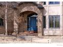 Charming front entrance features a brick archway, a bright blue front door, and manicured landscaping at 10391 E Goose Haven Dr, Lafayette, CO 80026