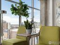 Cozy seating area with a table featuring green chairs, plants, and city views from large windows at 1700 Bassett St # 1013, Denver, CO 80202