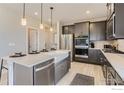 Modern kitchen with stainless appliances, a kitchen island with barstool seating, and gray cabinets at 2746 Bear Springs Cir, Longmont, CO 80503
