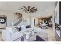 Bright open-concept living room boasts a ceiling fan, white sofa, and seamless flow into the dining and kitchen areas at 2746 Bear Springs Cir, Longmont, CO 80503
