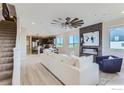 Bright living room with fireplace, TV, ceiling fan and open floor plan, next to the staircase at 2746 Bear Springs Cir, Longmont, CO 80503