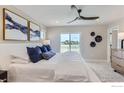 Bright bedroom featuring white bedding, blue accents, wall decor, and a sliding glass door to a balcony at 2746 Bear Springs Cir, Longmont, CO 80503