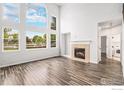 Bright living room with soaring ceilings, a fireplace, and large windows offering beautiful outdoor views at 6850 Sage Ave, Firestone, CO 80504