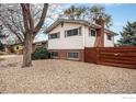 View of the home's exterior with vinyl siding, complemented by lush greenery and a well-maintained landscape at 10591 Park Ridge Ave, Longmont, CO 80504