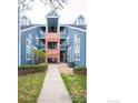 Exterior shows a walkway leading to the blue townhouse with brick accents and mature landscaping at 11197 Alcott St # C, Denver, CO 80234