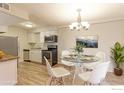 Dining area boasts a modern glass table, seating for four, and elegant chandelier lighting at 12180 Melody Dr # 203, Westminster, CO 80234