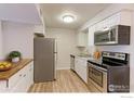 Well-maintained kitchen featuring stainless steel appliances, white cabinets, and wood-look flooring at 12180 Melody Dr # 203, Westminster, CO 80234