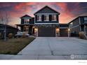 Inviting two-story house featuring a stone facade and a spacious three-car garage at dusk at 1401 Vantage Pkwy, Berthoud, CO 80513