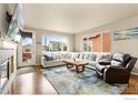 Bright living room with fireplace, large windows, a plush sofa, and hardwood floors at 1513 Chokeberry St, Berthoud, CO 80513