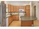 Well-equipped kitchen features light wood cabinets, modern appliances, and a functional island at 1518 Whitehall Dr, Longmont, CO 80504