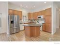 Spacious kitchen with stainless steel refrigerator, center island, and ample cabinet space at 1518 Whitehall Dr, Longmont, CO 80504