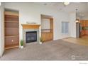 Cozy living room with built-in shelving, fireplace, and neutral carpet at 1518 Whitehall Dr, Longmont, CO 80504