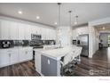 Modern kitchen with stainless steel appliances, a large center island with seating, and sleek cabinetry at 15788 Xanthia Way, Thornton, CO 80602