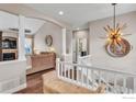 Welcoming foyer with hardwood floors, staircase, and decorative lighting fixtures leading to the living area at 16620 Umpire St, Hudson, CO 80642