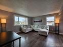Cozy living room featuring hardwood floors, a large sectional sofa, and bright windows showcasing neighborhood views at 2252 Smith Dr, Longmont, CO 80501