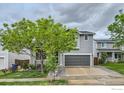 Two-story home with gray siding, two-car garage, and a lush tree in the front yard at 230 Bonanza Dr, Erie, CO 80516
