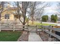 Charming yellow home with a fenced yard, concrete walkway and mature trees at 247 Rendezvous Dr, Lafayette, CO 80026
