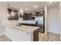 Modern kitchen with dark cabinets, stainless steel appliances, and stylish pendant lighting at 2754 Bear Springs Cir, Longmont, CO 80503