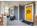 Inviting front porch with a vibrant yellow door, decorative wreath, and modern seating area at 301 Indian Peaks W Trl, Lafayette, CO 80026