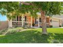 A charming brick home features a welcoming front porch, framed by a mature tree and a lush green lawn at 3050 N Torreys Peak Dr, Superior, CO 80027