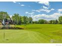 Scenic golf course view showcasing lush green fairways, mature trees, and a tranquil pond with mountains in the background at 567 Manorwood Ln, Louisville, CO 80027