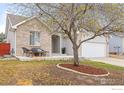 Inviting front yard with mature tree, patio seating, and a well-maintained exterior on a sunny day at 629 Mcclure Ave, Firestone, CO 80520