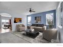 Bright living room with large windows, ceiling fan, modern furnishings, and an open view to the dining area at 6297 Clayton Cir, Frederick, CO 80530