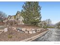 A beautifully landscaped townhome exterior featuring a rock wall, lush greenery, and manicured lawn at 821 Stony Mesa Pl, Castle Rock, CO 80108