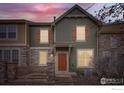 Inviting two-story townhome with stone accents, wooden shutters, a charming front porch, and an address number of 821 at dusk at 821 Stony Mesa Pl, Castle Rock, CO 80108