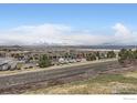 Scenic view of the neighborhood with commercial buildings, a road, and distant mountains under a blue sky with clouds at 821 Stony Mesa Pl, Castle Rock, CO 80108