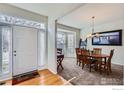 Bright foyer with hardwood floors transitioning to a carpeted dining area featuring a bay window and chandelier at 1534 Chukar Dr, Longmont, CO 80504