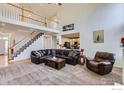 Expansive living room with high ceilings, a staircase, comfortable furniture, and an open view to the kitchen at 1534 Chukar Dr, Longmont, CO 80504