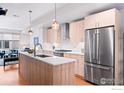 Bright kitchen with stainless steel appliances, wood cabinets, and a central island with sink at 1836 Grove St # 105, Denver, CO 80204