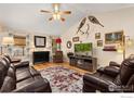 Cozy living room with hardwood floors, vaulted ceilings, a ceiling fan and a decorative fireplace at 2518 Palmer Ave, Mead, CO 80542