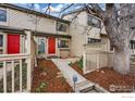 Inviting townhome exterior with red door, fenced yard, mature tree, and fresh mulch landscaping at 4015 Wonderland Hill Ave, Boulder, CO 80304