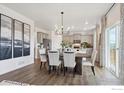 Bright dining area with wood floors, modern chandelier, and a view into the kitchen and outdoor area at 6512 13Th St, Frederick, CO 80530