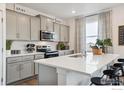 Modern kitchen with grey cabinets, white countertops, stainless steel appliances, and eat-in island with seating at 6512 13Th St, Frederick, CO 80530