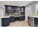 Stylish kitchen features navy blue cabinetry, stainless steel appliances, and a unique backsplash at 778 S Nome St, Aurora, CO 80012
