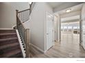 Entryway featuring light hardwood floors, staircase with railing, and white doors leading to the living area at 786 Griffith St, Lochbuie, CO 80603