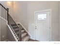 Bright foyer featuring a carpeted staircase with a modern railing and a white front door at 786 Griffith St, Lochbuie, CO 80603