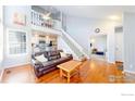 Bright living room featuring hardwood floors, a staircase, and an open view to the kitchen at 8300 W 87Th Dr # B, Arvada, CO 80005