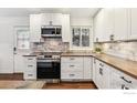 Well-lit kitchen featuring white cabinets, stainless steel appliances, and stylish marble backsplash at 94 Spring Ln, Boulder, CO 80302