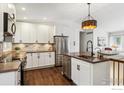 Modern kitchen with white cabinets, stainless steel appliances, stone countertops and hardwood floors at 94 Spring Ln, Boulder, CO 80302