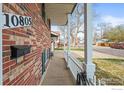 The covered brick porch has classic white columns and a white railing, offering a cozy entry at 10805 Verna Ln, Northglenn, CO 80234