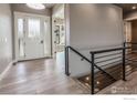 Inviting entryway with glass door, hardwood floors, modern railing and natural light at 1288 Eliza Ave, Berthoud, CO 80513