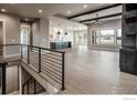Open living space with modern railing, neutral palette, lots of natural light and kitchen in the background at 1288 Eliza Ave, Berthoud, CO 80513