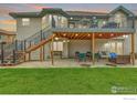 Spacious backyard featuring a covered patio, outdoor dining area, and lush green lawn, perfect for entertaining at 1730 Crestone Dr, Longmont, CO 80504