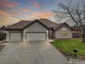 Lovely single-story home with a spacious driveway, three-car garage, and manicured lawn, set against a vibrant sky at 1730 Crestone Dr, Longmont, CO 80504